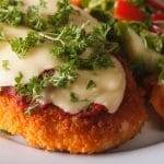 Close-up of Chicken Parmesan with fresh salad.