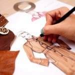 Designer sketching fashion illustration with pencil and swatches.