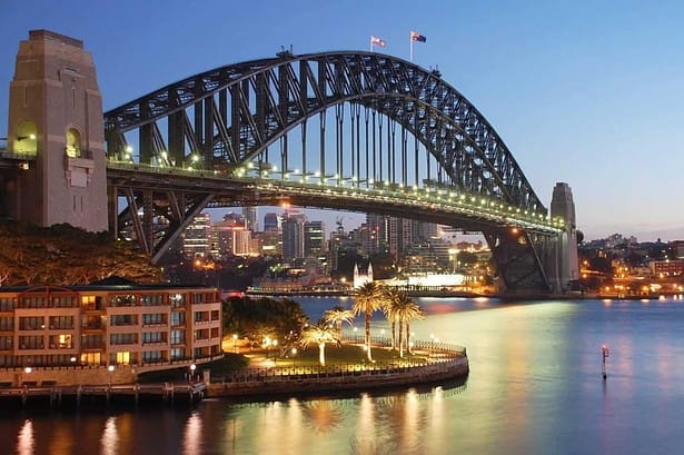 Sydney Harbour Bridge illuminated at dusk.