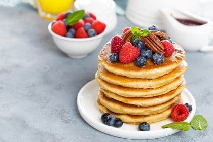 Fresh berry-topped pancakes with pecans on a plate.