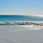 Crystal clear turquoise waves crashing on serene beach.