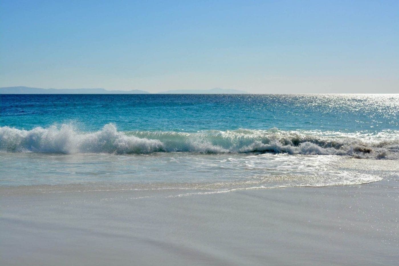 Crystal clear turquoise waves crashing on serene beach.
