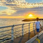 Boy walking on St. Kilda Jetty at sunset.