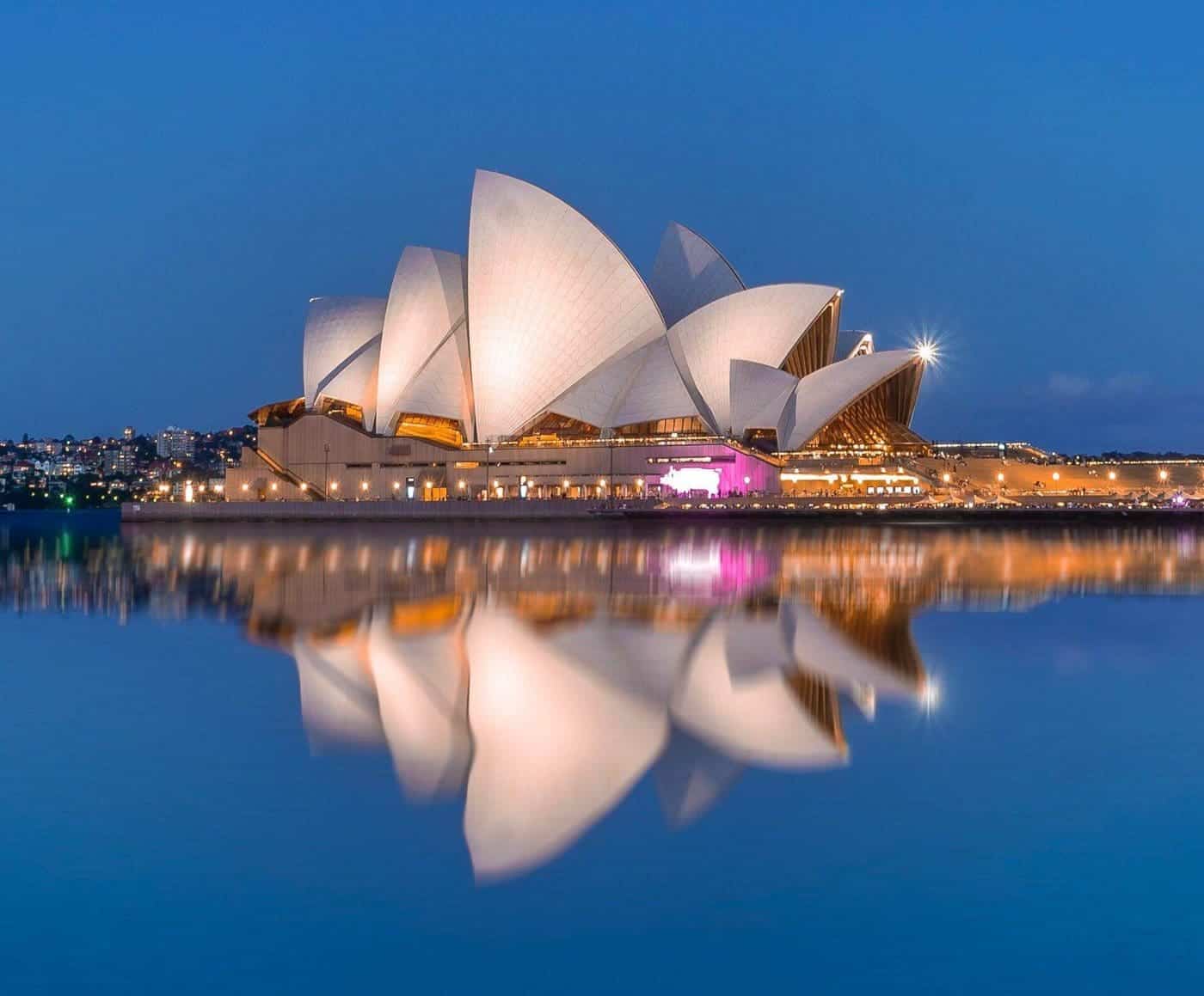 Sydney Opera House illuminated at night with reflection.
