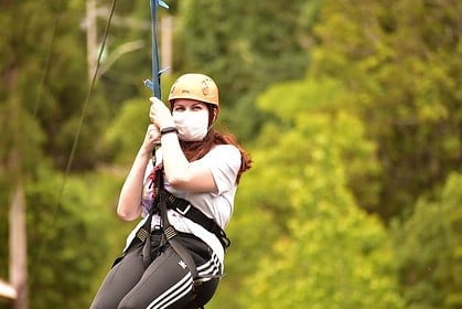 Woman ziplining in an outdoor adventure park.