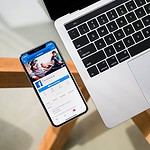 Laptop and smartphone on desk displaying social media.