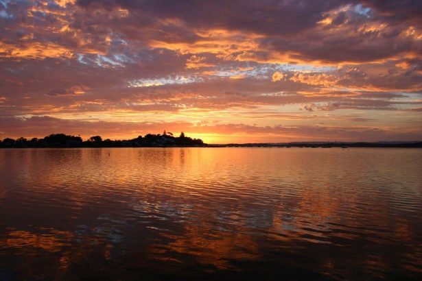 Sunset over tranquil lake with clouds and reflections