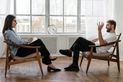 Two people having a conversation on wooden chairs.