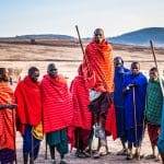 Maasai tribe members in colorful traditional clothing with spears.