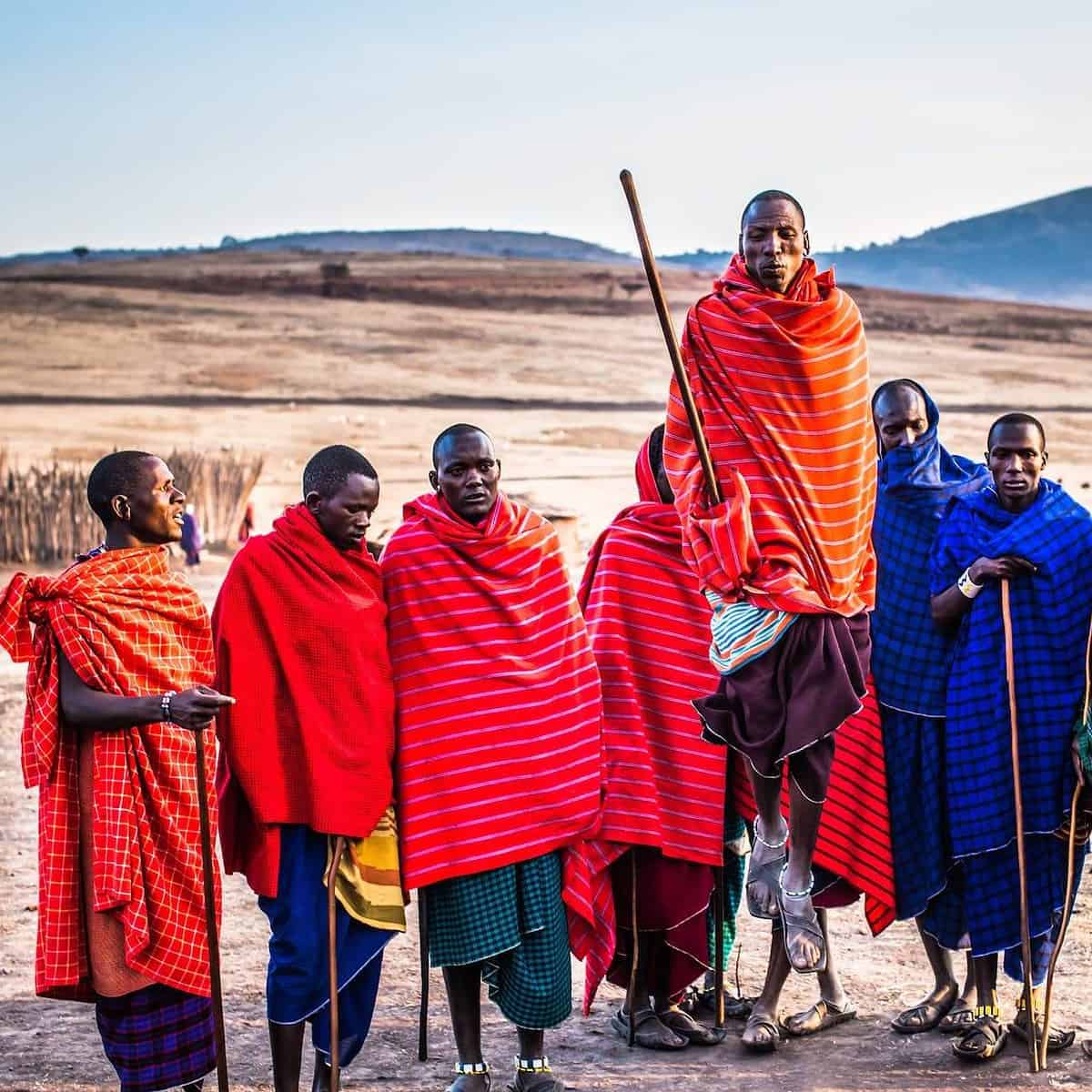 Maasai tribe members in colorful traditional clothing with spears.