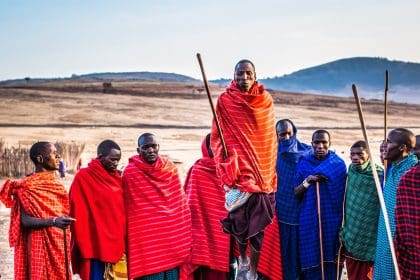 Maasai tribe members in colorful traditional clothing with spears.