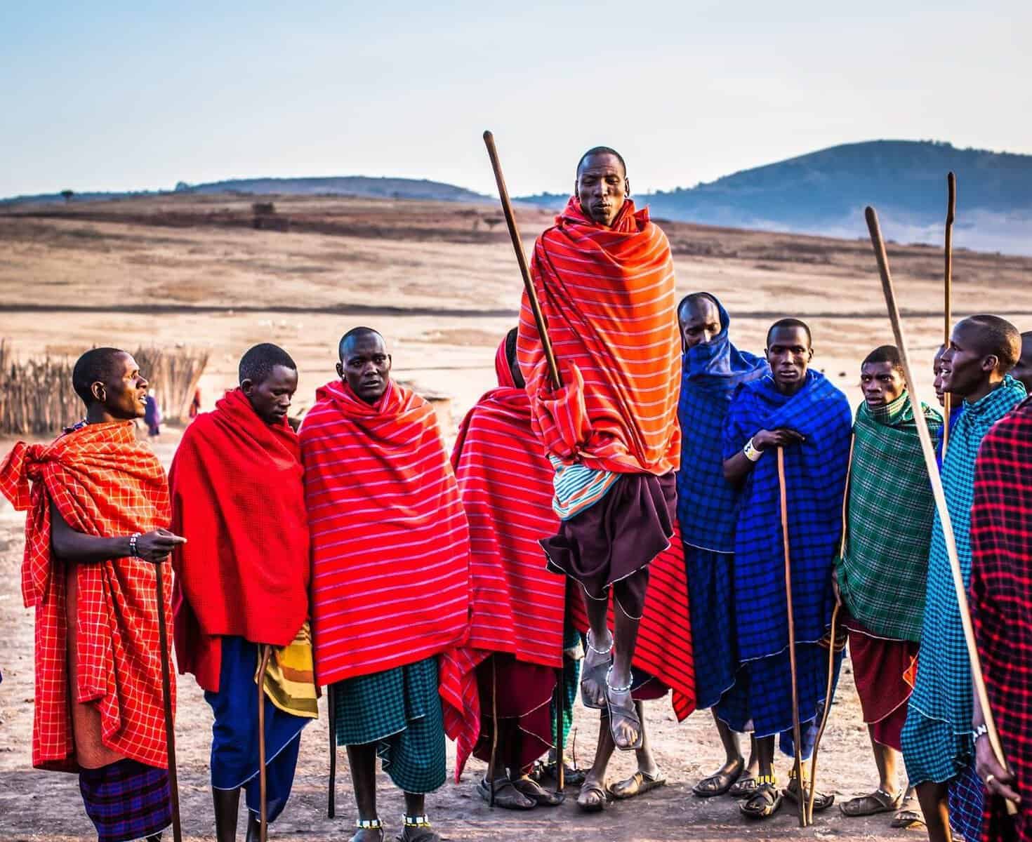Maasai tribe members in colorful traditional clothing with spears.