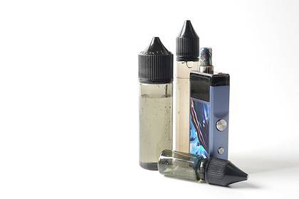 E-cigarette with refill bottles on white background.
