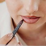 Close-up of person applying lip liner for makeup enhancement