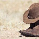 Cowboy hat and boots in desert setting.