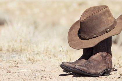 Cowboy hat and boots in desert setting.