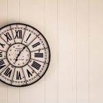 Vintage Roman numeral clock on white wall for interior design inspiration.