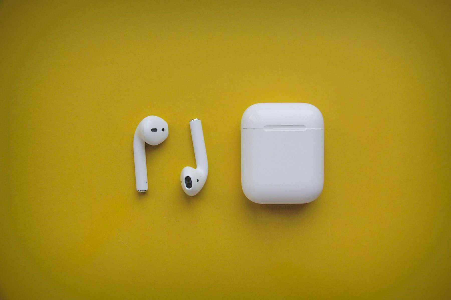 how to change the name on airpods: Apple AirPods with case on vibrant yellow background.