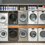 Row of washing machines at a modern laundromat with prices.