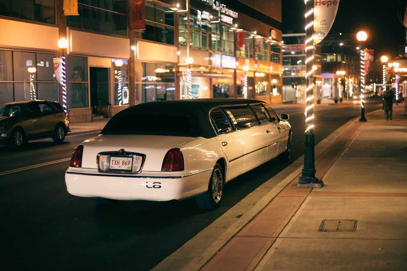 White stretch limousine parked on city street at night.