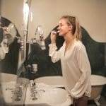 Woman brushing teeth in bathroom mirror