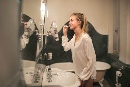 Woman brushing teeth in bathroom mirror